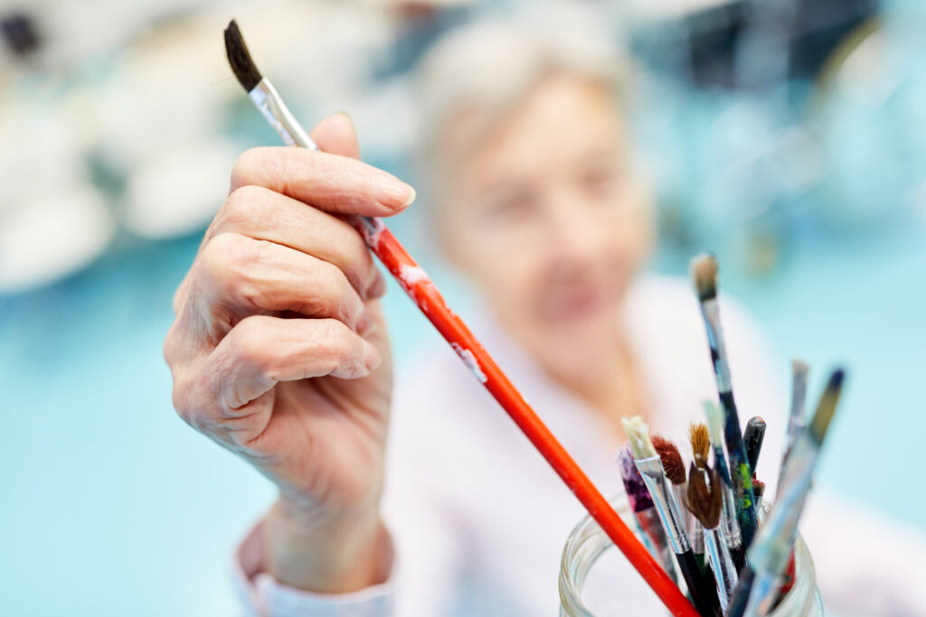 A senior resident enjoys a painting activity as part of a vibrant long-term care program. Long-term care facilities provide enriching experiences that promote well-being, creativity, and quality long-term health care in a supportive long-term nursing home setting.