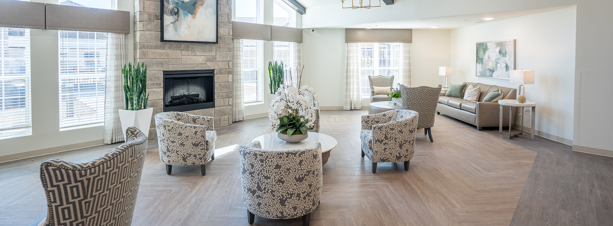 A spacious and elegantly designed common area inside a nursing home, featuring high ceilings, modern furnishings, and abundant natural light. This senior living facility offers skilled nursing services in a warm, inviting elderly care center where residents can relax and socialize in comfort.